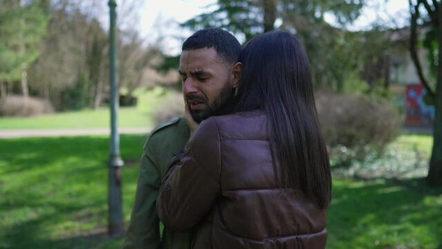 Depressed young man being consoled by woman embrace outside at park. Desperate person suffering from mental illness covering face with hand