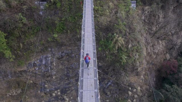 Aerial view of man hiking on the Jhinu Danda suspension bridge in Nepal.