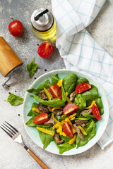 Warm salad of young spinach, chicken liver, tomatoes and grilled peppers with spices and balsamic. Healthy keto diet low carb. View from above.