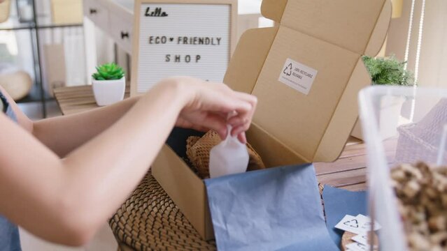 Eco vendor go green packaging parcel carton box in net zero waste store asian seller retail shop. Earth care day small SME owner asia people wrap reuse brown paper pack gift reduce plastic free order.