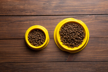 Pet care concept. Bowl of dry food on wooden background. Top view.