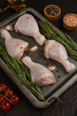 Raw chicken legs, spicy marinated drumsticks in cast iron sheet pan on dark background