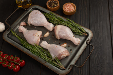 Raw chicken legs, spicy marinated drumsticks in cast iron sheet pan on dark background