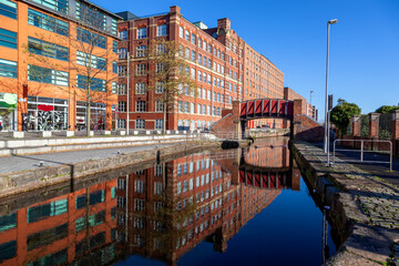 Reflection of Footbridge and warehouses  in Murray Mills Redhill Street Ancoats Manchester UK
