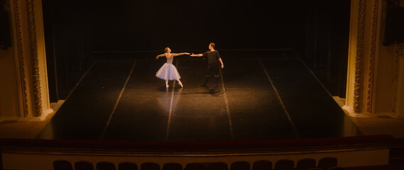 Wide shot of ballet dancers practicing choreography on classic theater stage. Man and woman prepare...