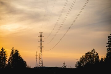 Silhouette of electric transmission tower against sunset sky