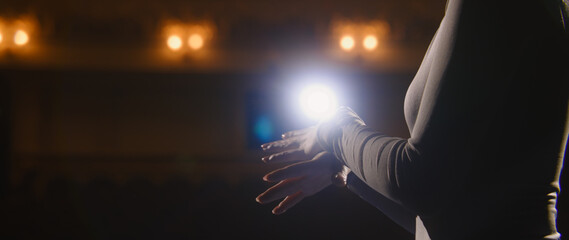 Close up shot of ballerina discussing performance with partner on theater stage. Ballet female dancer gestures and talks about choreography on rehearsal. Illuminated theatrical hall. Classical ballet.