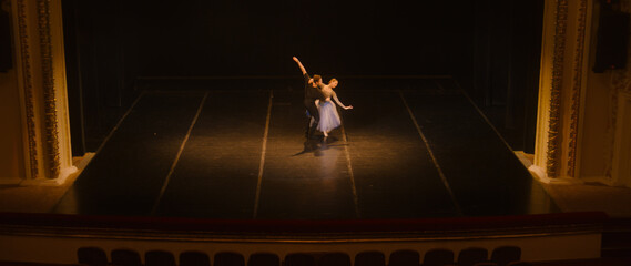 Wide shot of ballet dancers practicing choreography on classic theater stage. Man and woman prepare...