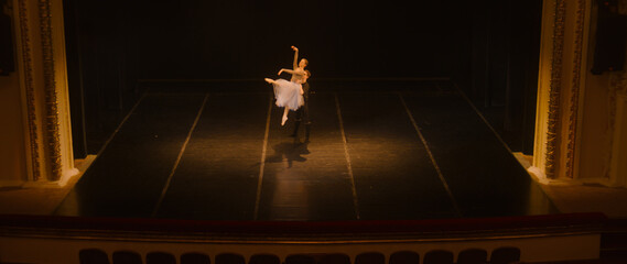 Wide shot of ballet dancers practicing choreography on classic theater stage. Man and woman prepare...