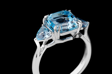 Beautiful gold ring with aquamarine and diamonds on a black background