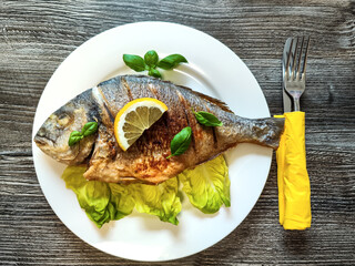 Golden fried sea bream fish on plate with vegetables, top view