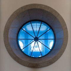 Indoor round window with metal frame giving a view in the next room. Picture taken indoor in Alfandega conference center in Porto, Portugal.