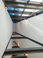 Rays of sunlight shining through glass and metal modern foyer with triangular design.