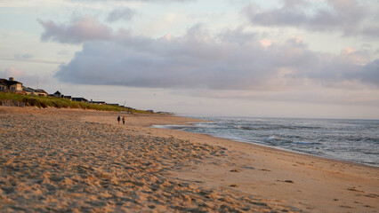 Cloudy sunrise at the beach with two people in the distance