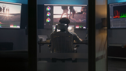 African American colorist does color grading in professional software on computer. Process of...