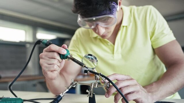 Teenager Student soldering electronics cable, learning engineering and technology 