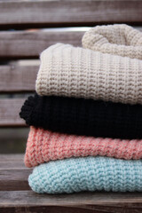 Fototapeta na wymiar Stack of woolen sweaters folded on wooden background