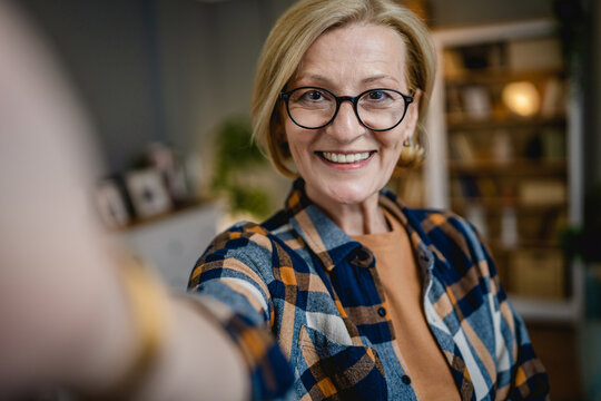Portrait of one mature blonde caucasian woman with eyeglasses at home