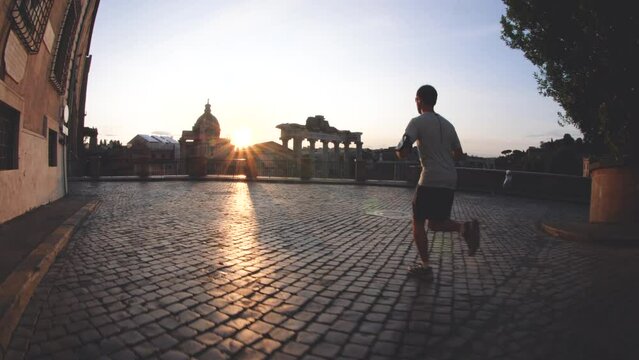 Young man running jogging in front of the Roman Forum at sunrise. Historical imperial Foro Romano in Rome, Italy from panoramic point of view.