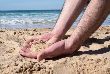 Touching the beach. Shot of a man with a handful of sand falling through his fingers.