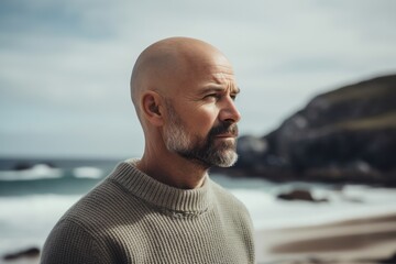 Fototapeta premium Portrait of a handsome mature man standing on the beach by the sea.
