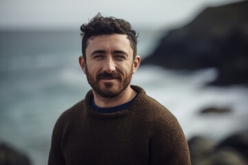 Portrait of a handsome bearded man standing in front of the ocean