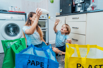 Mother using game is teaching kid how to recycle help the boy aware environmental importance - mom educates son sort garbage into different bins on kitchen. Family sorting garbage at home. recycling