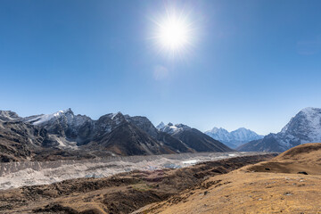 Khumbu glacier slowly flowing from the slopes of Mount Everest down to the valley with noon sun above