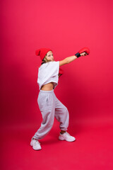 Fototapeta na wymiar Cute little girl in boxing gloves on red background studio