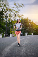 attractive asian woman healthy jogging exercise with transparent plastic water bottle in park outdoor at the evening