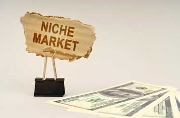 There is money on the table, next to it is a cardboard sign with the inscription - Niche Market