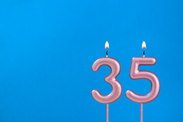 Number 35 - Burning anniversary candle on blue foamy background