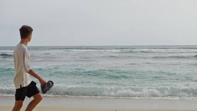 A Beautiful Landscape, a Deserted Beach, far away a Handsome Naked Man Approaches the Ocean and Dives into the Water, Slow motion