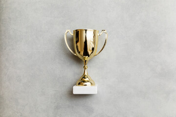 Simply flat lay design winner or champion gold trophy cup on concrete stone grey background....