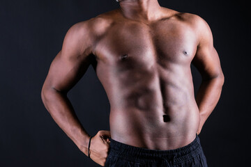 Isolated african muscular man with dumbbells on dark studio background. Strong shirtless black guy