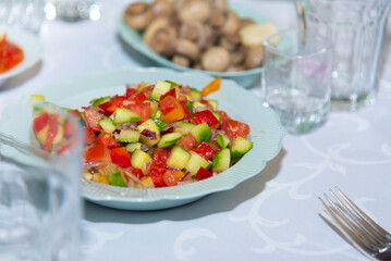 Fresh spring salad on white plates staying on banquet table. Sliced tomato, pepper, cucumber. healthy vegetarian dishes. Selective focus