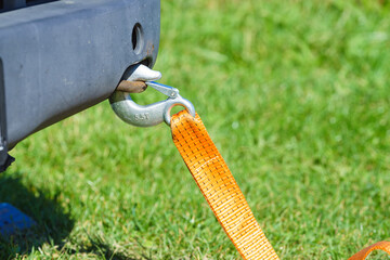 Tow hook with orange strap on car. Towing equipment.