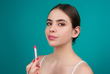 Obraz premium Lipstick, beauty and cosmetics. Beautiful woman applying lipstick on lips. Mockup for cosmetics, makeup. Lips color product, balm cosmetic on studio background.