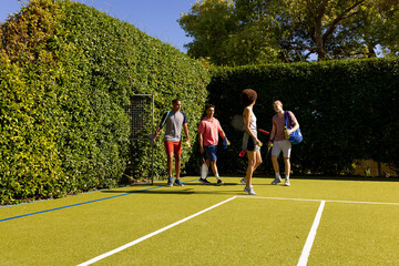 Obraz premium Happy diverse group of friends arriving together at tennis court
