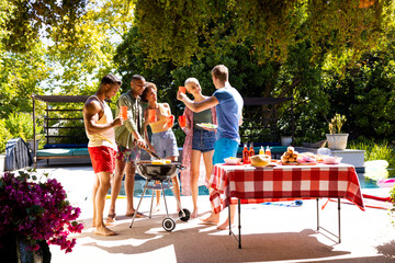 Happy diverse group of friends having pool party, barbecuing in garden