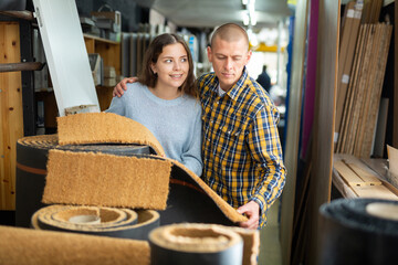 Couple of positive customers holding flooring samples in hardware store