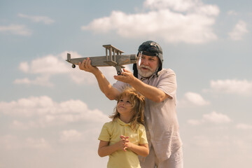 Grandfather and grandson having fun with toy plane on sky. Child dreams of flying, happy childhood with granddad.