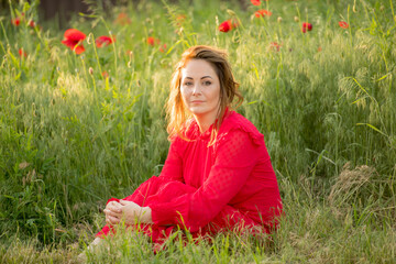 portrait of a woman with red flowers in a red dress in a field