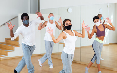 Group of multinational activity people in protective masks practicing dance techniques