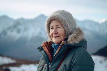 Fototapeta na wymiar Portrait of an elderly woman in a winter jacket against the background of mountains