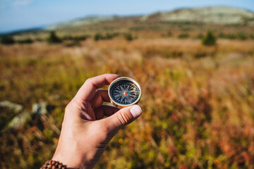 Retro compass for orienteering, hand holds magnetic compass, arrow to the north, sweat search, hike in the mountains, trekking alone, survival in the forest.