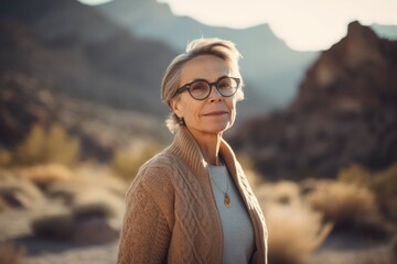 Portrait of a beautiful mature woman in glasses on a background of mountains