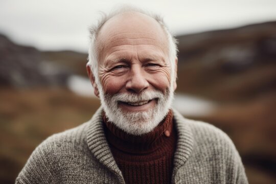 Portrait of a senior man with grey hair and beard smiling in the countryside