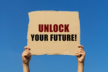 Unlock your future text on box paper held by 2 hands with isolated blue sky background. This...
