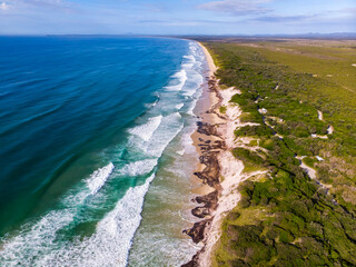 Aerial view of massive large sand dunes and Pacific ocean at sunset. Hat Head National Park, NSW, Australia